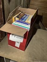 Box with assorted fiction novels from various authors, labeled as 'Fiction'.