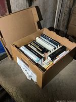 Box filled with assorted novels, showing arrangement and condition of books inside.