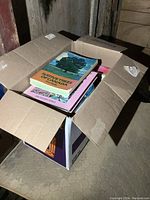 Box full of gardening books, with two visible titles on top: 'Native Trees of Canada' and 'The Complete Book of Hardy Perennials'.