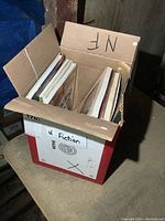Photo of a cardboard box labeled 'N Section' filled with various books and sheet music.