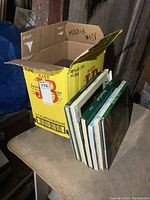 Box containing multiple gardening and outdoors books, some partially visible with green covers and various titles.