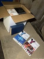 Box of novels showing some volumes inside and two graphic novels on the floor