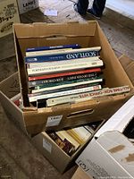 Photo showing large cardboard box stuffed with big hardcover books of mixed topics and genres.