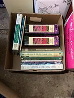 View of the open box displaying various gardening and medicinal plant books stacked horizontally and vertically, showing titles and covers.