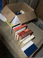 Top view of box full of history books, mostly hardcover, stacked inside and outside the box.