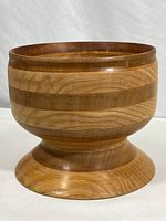 Full side view of wood bowl showing rounded body and wide base with wood grain and striped pattern