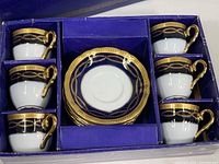 Set of six Alpine Cuisine demitasse cups and saucers arranged in original blue box with gold trim.