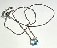 Full view of sterling silver chain necklace with blue crystal pendant and small accent beads.
