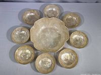 Top down view showing large central scalloped bowl surrounded by eight smaller matching bowls in circular pattern.