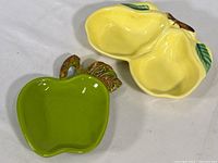 Yellow double pear-shaped ceramic spoon rest shown from above and side angle, visual condition and shape
