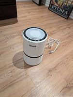 Levoit air purifier unit standing on the floor showing top control panel and power cord.