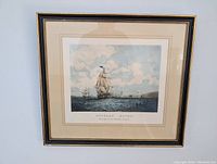 Framed artwork showing full ship print with black wooden frame and visible minor chipping.
