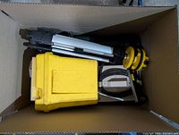 Photo showing laser level equipment, including a small tripod and yellow space heater in a box