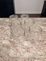 Six clear glass canning jars grouped together on a countertop, showing size and shape.