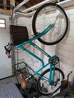 Teal Supercycle Pathway bicycle hanging vertically showing side profile and front basket
