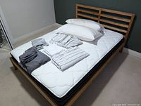 Bed frame with mattress and assorted bedding items arranged