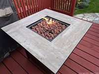 Fire table lit, flame visible among lava rocks in central burner