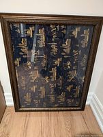 Front view of framed fabric print showing multiple gold landmark illustrations on dark background