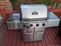 Closed Broil-Mate propane gas barbecue grill showing four control knobs, side burner, and two-door cabinet.