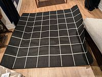 Black side with white grid lines laid on wooden floor.
