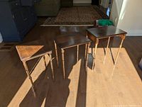 Three wooden nesting tables arranged side by side, showing the varying sizes and turned legs.