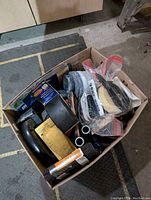 Photo of box with painting tools including brushes, sanding blocks, paint rollers, sanding sheets and more