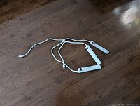 Three white power strips laid out on wood floor showing overall size and cords
