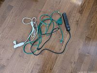 Three power strips of different colors and lengths arranged on a wooden floor.