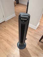 Full view of the Seville Classics tower fan standing on a wooden floor against a white wall.