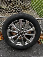 Full assembled wheel and tire leaning against chain-link fence