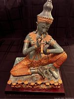Front view of the bronze Thai Gandharva figure playing a flute, showing detailed gilding and posture.