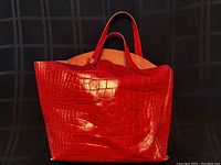 Front exterior view of red leather Furla tote with crocodile embossing and two shoulder straps.