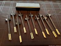 Full set of 10 pairs Japanese chopsticks with silver tips arranged with stands and presentation box on table.