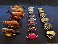 Full set of 20 napkin rings arranged in rows showing wood carved animals, metal elephant figures, and lacquered horn rings with animal prints.