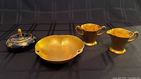 Top view of Pickard gold glazed china including sugar bowl, creamer, candy dish, and blue Bavarian trinket bowl with lid.
