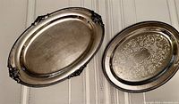 Both silverplated trays on striped fabric, showing size and overall condition.