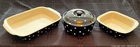 Three-piece set of Spode Baking Days black ceramic bakeware with white polka dots: rectangular lasagna pan, square cake pan, and covered round baking dish.