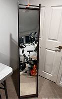 Front view of the full-length wood framed standing mirror showing its reflective surface and part of the metal stand behind.
