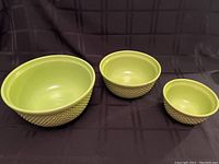 Set of three lime green nesting ceramic mixing bowls arranged side by side