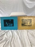 Two framed black and white Manhattan photographic prints displayed side by side. Frames have colored glass, turquoise blue and amber/yellow.