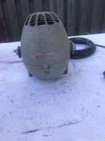 Rear view showing the curved top with ventilation slots and a metal plate with possible manufacturer information, along with mounting hardware.