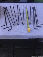 Eight black metal hairpin legs laid out flat with measuring tape showing 19 inch length