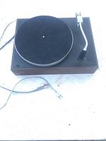 Full view of vintage AR turntable on white surface showing overall unit, tonearm, and attached cables.