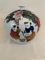 Front view of the vase showing hand painted children figures with a bowl and foliage.