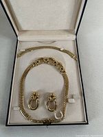 Box containing necklace, bracelet, and pair of clip-on earrings arranged on white velvet lining