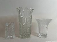 Three frosted crystal glass vases displayed side by side showing different shapes and sizes