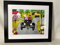 Full framed Maud Lewis print showing vintage car scene with flowers and houses.