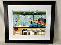 Framed Maud Lewis print showing the full artwork with black frame and white mat, depicting coastal scene with boats and dock.