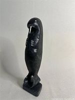 Front and left side profile of the standing walrus stone sculpture showing base and front flippers.