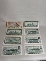 Collection of mostly $1 and $2 Canadian bills laid flat showing front and back designs including multiple identical bills